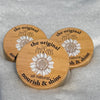 Three wooden coasters with a sunflower design on a snowy surface
