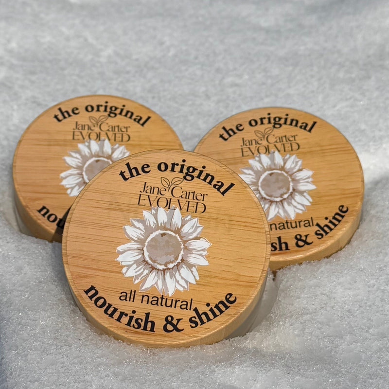 Three wooden coasters with a sunflower design on a snowy surface